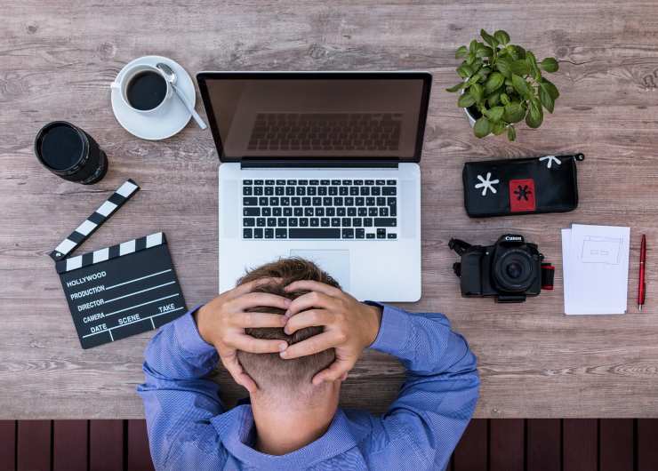 Un ragazzo si tiene la testa tra le mani davanti a un computer portatile