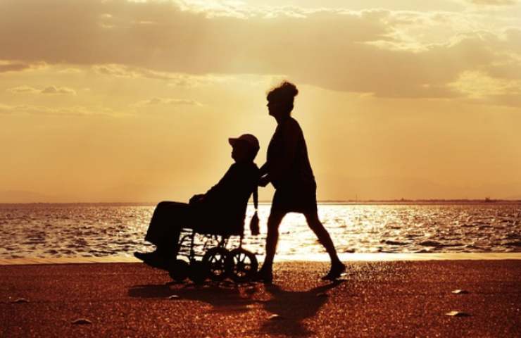 Persona al tramonto su sedia a rotelle