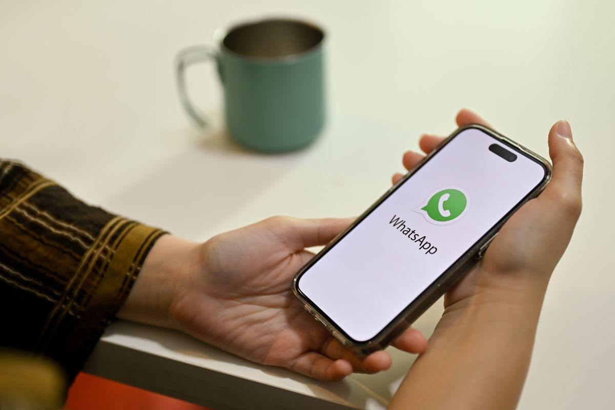 Smartphone con logo WhatsApp tra le mani