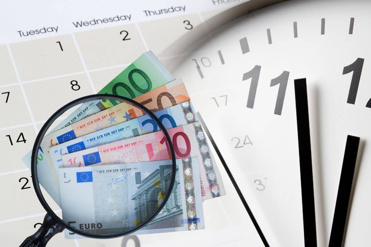 Calendario con un orologio e una lente ingrandimento su delle banconote euro