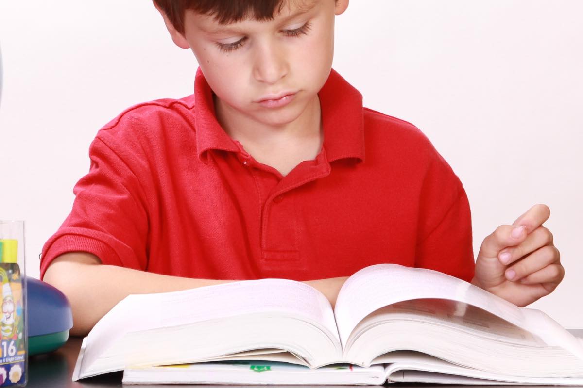 Bambino assorto nella lettura di un testo scolastico